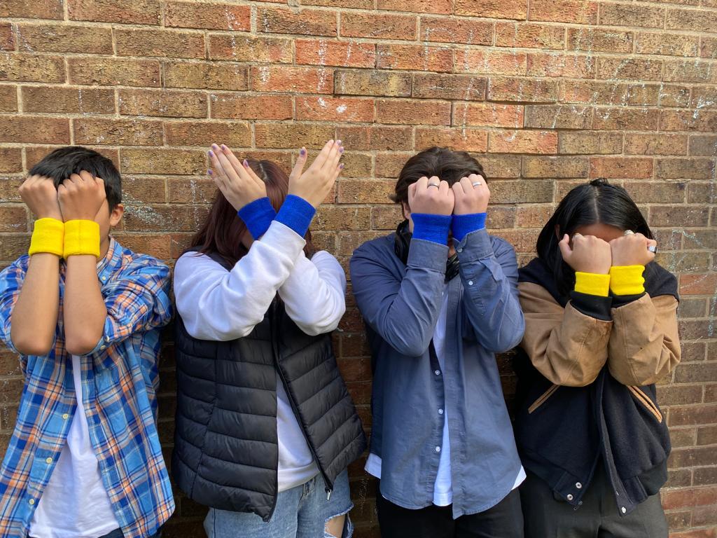 young people with arms across face wearing ukraine colours