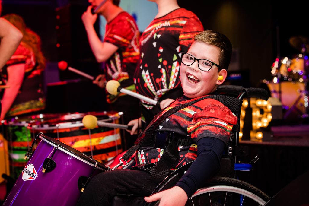 young person playing the drums smiling
