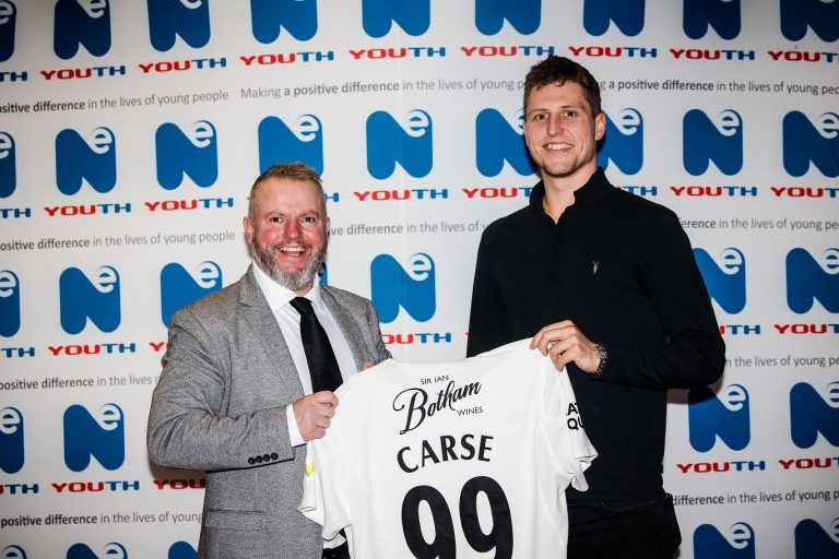 Two men holding up a signed shirt