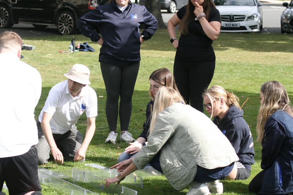 A group of colleagues work together in a problem-solving task outdoors.